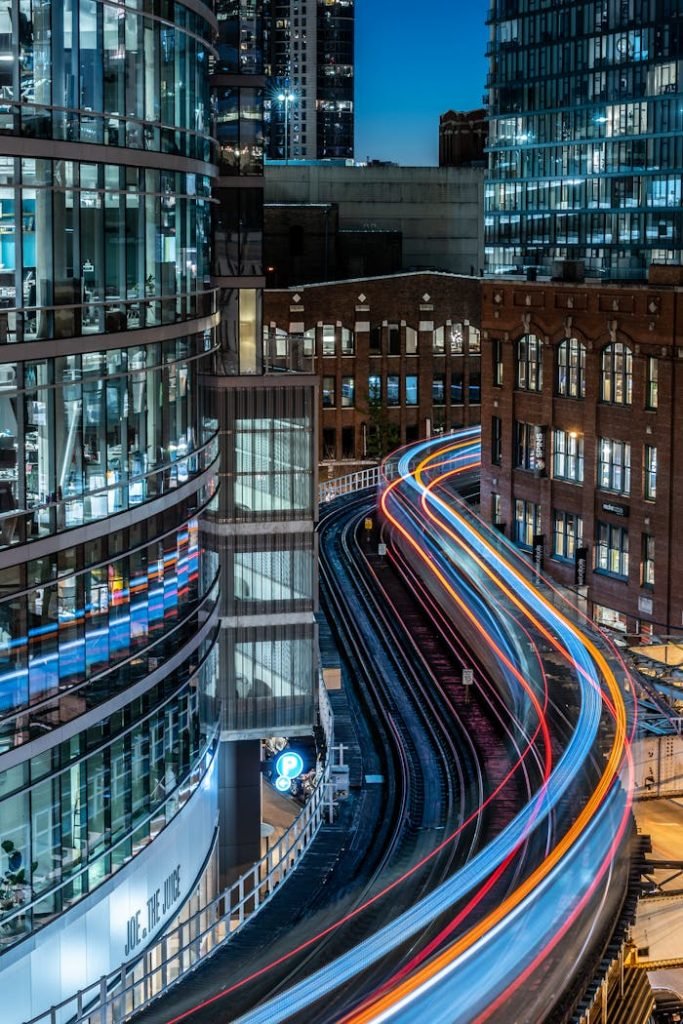 Long exposure of urban train tracks creating vibrant light trails in a modern cityscape at night.
